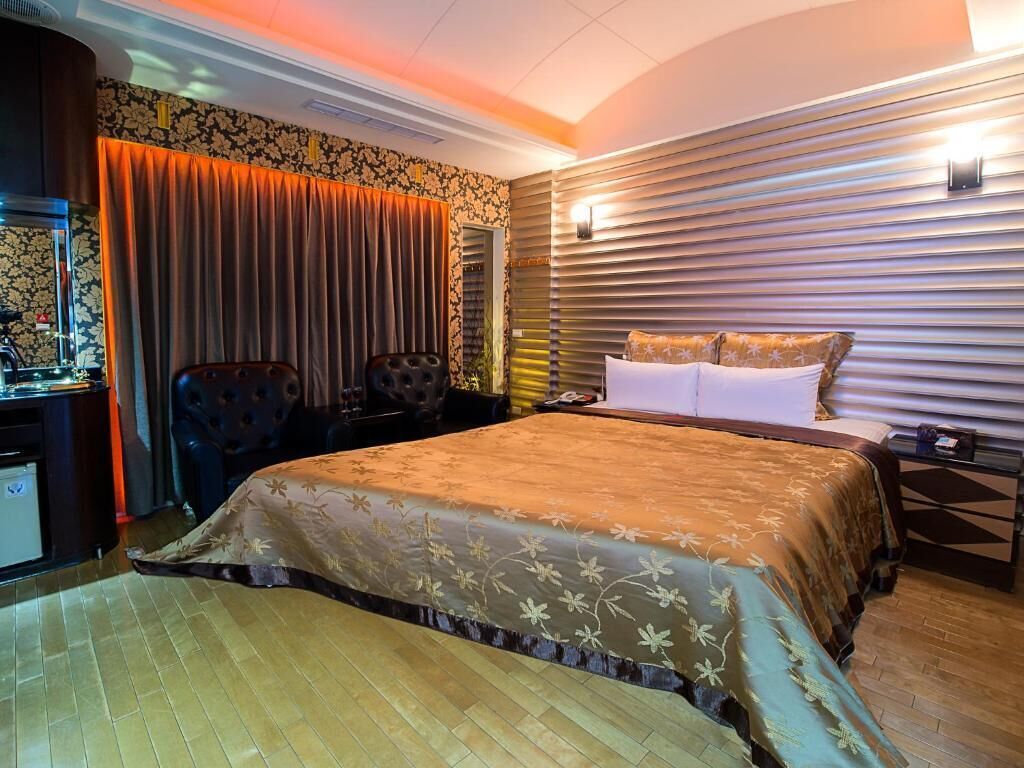 A hotel room with a large bed, a desk with a computer, and a chair.