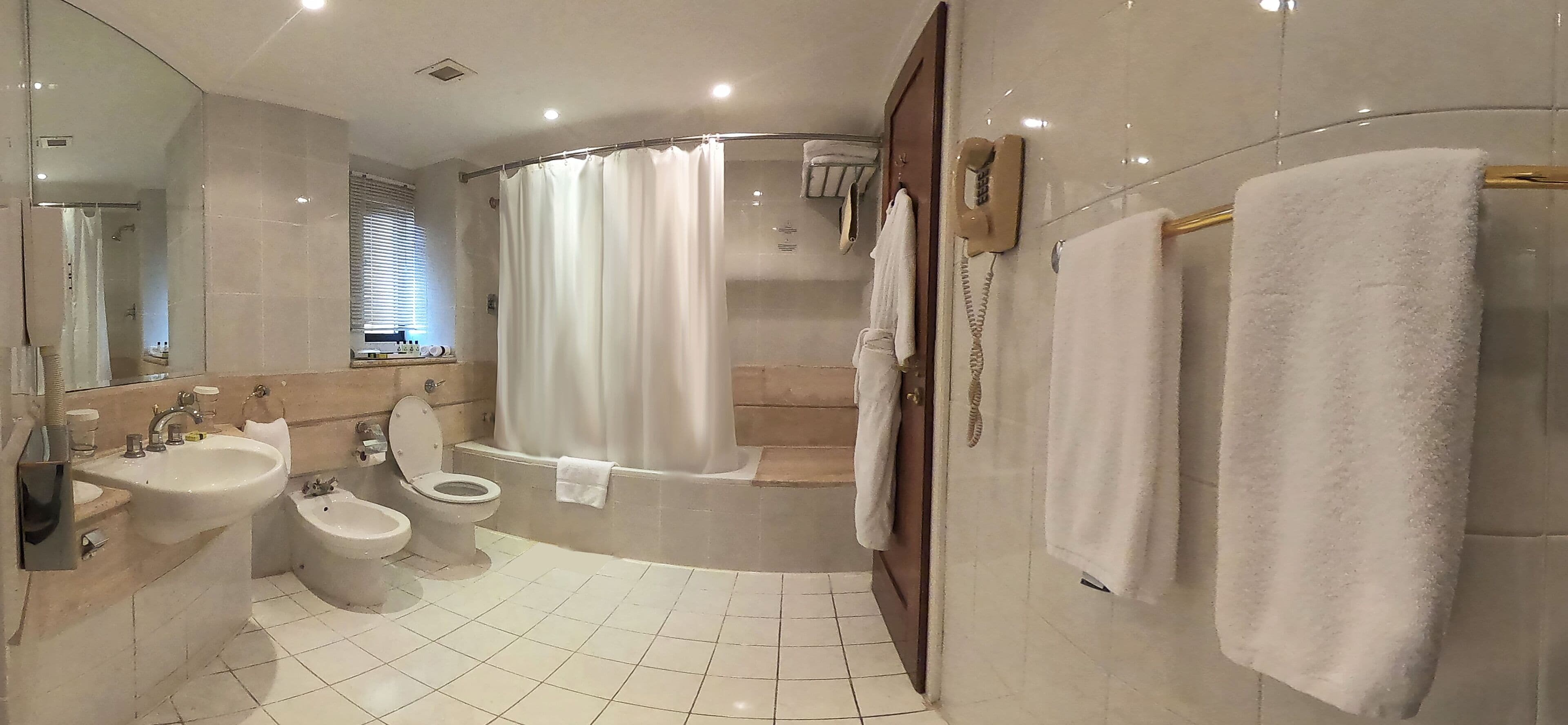 Un bany modern amb banyera, dues dutxes, un vàter i un lavabo.
