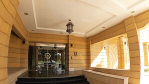 Una entrada imponente con puerta de cristal, una escalera y un farol decorativo.