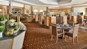 Un amplio vestíbulo de hotel con una recepción de mármol, varias zonas de estar y una alfombra estampada.