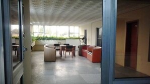 An open-plan office space with a kitchenette, a dining area, and a seating area with a sofa and chairs. - Marian Hotels (Calabar)