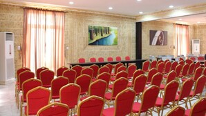 A conference room with rows of red chairs, a long table, and two paintings on the walls. - Marian Hotels (Calabar)