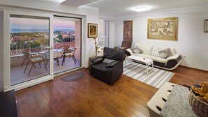 A living room with a balcony, a sofa, a coffee table, and a dining area with chairs and a table.