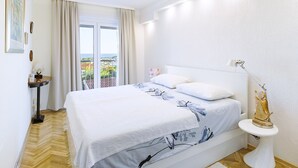 A modern bedroom with a large bed, a bedside table, a nightstand, and a view of the outdoors.
