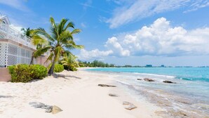 Una playa con agua turquesa cristalina, arena blanca y palmeras.