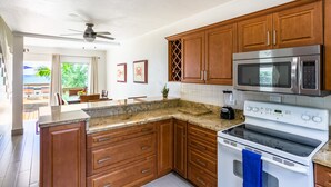 Una cocina con armarios de madera, microondas empotrado, estufa y ventilador de techo.