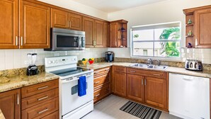 Una cocina moderna con armarios de madera, electrodomésticos de acero inoxidable y una ventana con vistas a la vegetación.