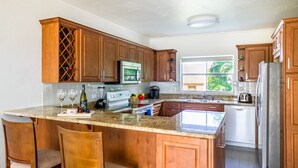 Una cocina con armarios de madera, encimera de granito, enfriador de vino empotrado y lavavajillas.