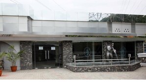 A modern building with a stone facade, large glass windows, and a metal sculpture in front. - Rita Lori Hotel Lagos (Lagos)