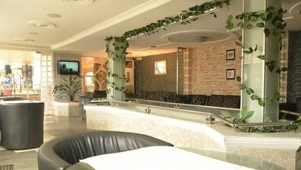 A lobby with a reception desk, black leather seating, and decorative plants. - Rita Lori Hotel Lagos (Lagos)