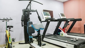 A gym with exercise equipment including a treadmill, stationary bike, and weight machines. - Paconsu Suites (Calabar)