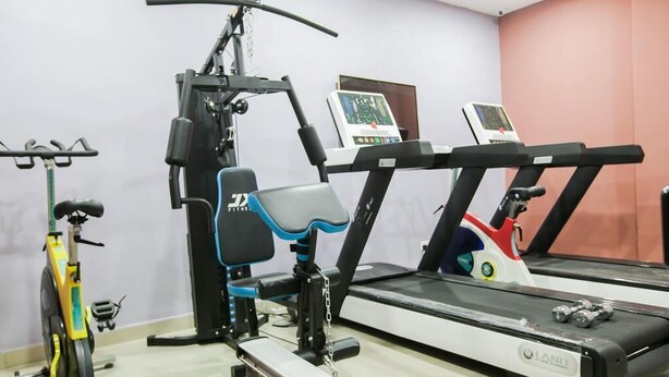 A gym with exercise equipment including a treadmill, stationary bike, and weight machines. - Paconsu Suites (Calabar)