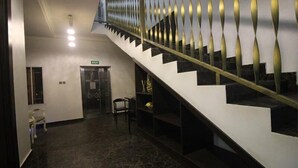 A modern staircase with a metal railing, a chair, and a door marked "EXIT". - Paconsu Suites (Calabar)