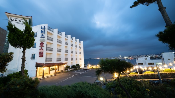 A modern hotel with a white facade, multiple balconies, and a view of the sea. - Hotel Navis (Jeju City)