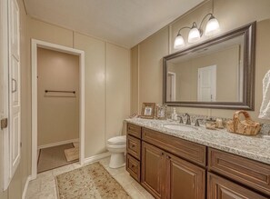 A bathroom with a large mirror, a sink, and a toilet. - Bungalow on the Guadalupe River - Seguin, TX (Seguin)
