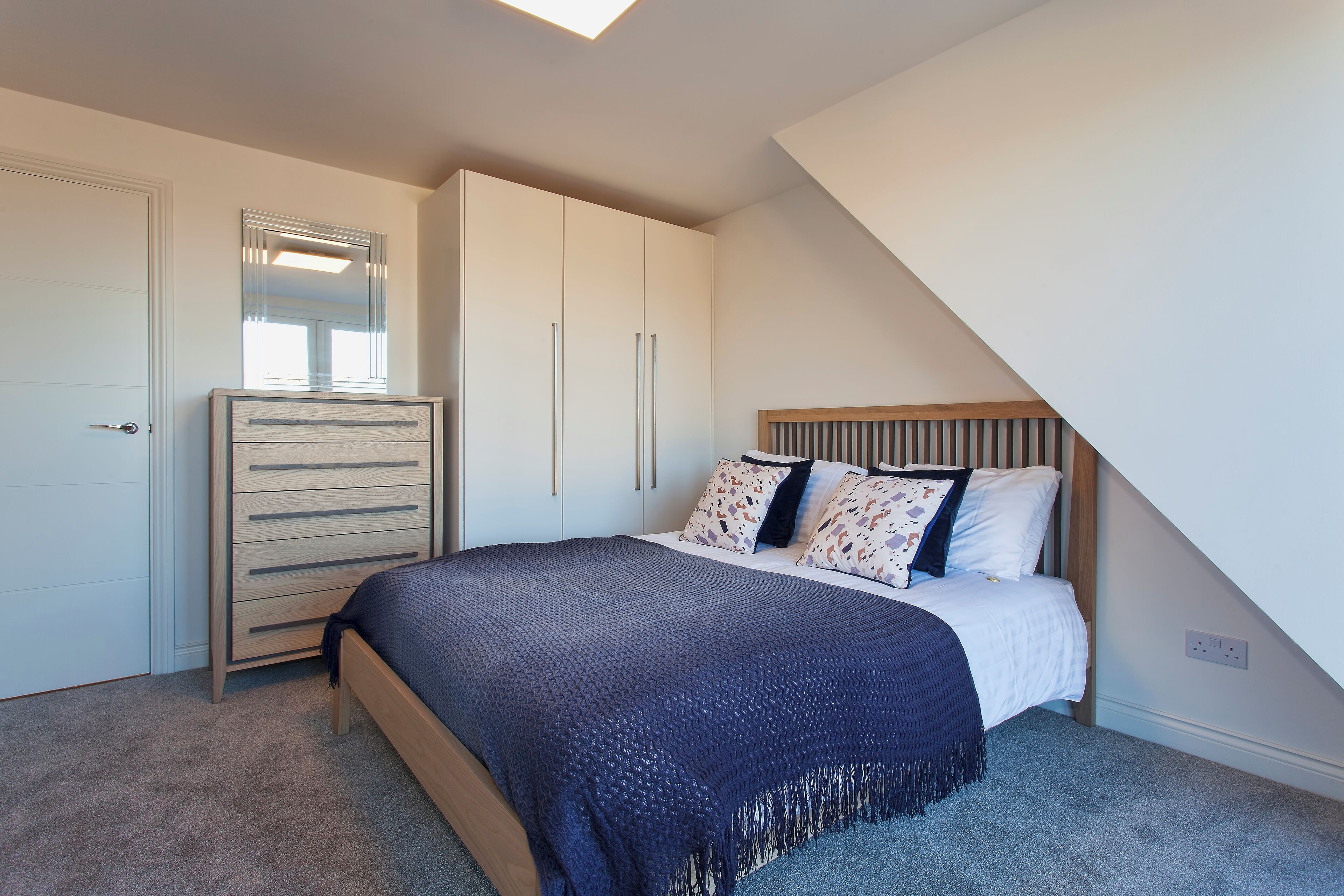 A bedroom with a bed, a dresser, and a wardrobe.