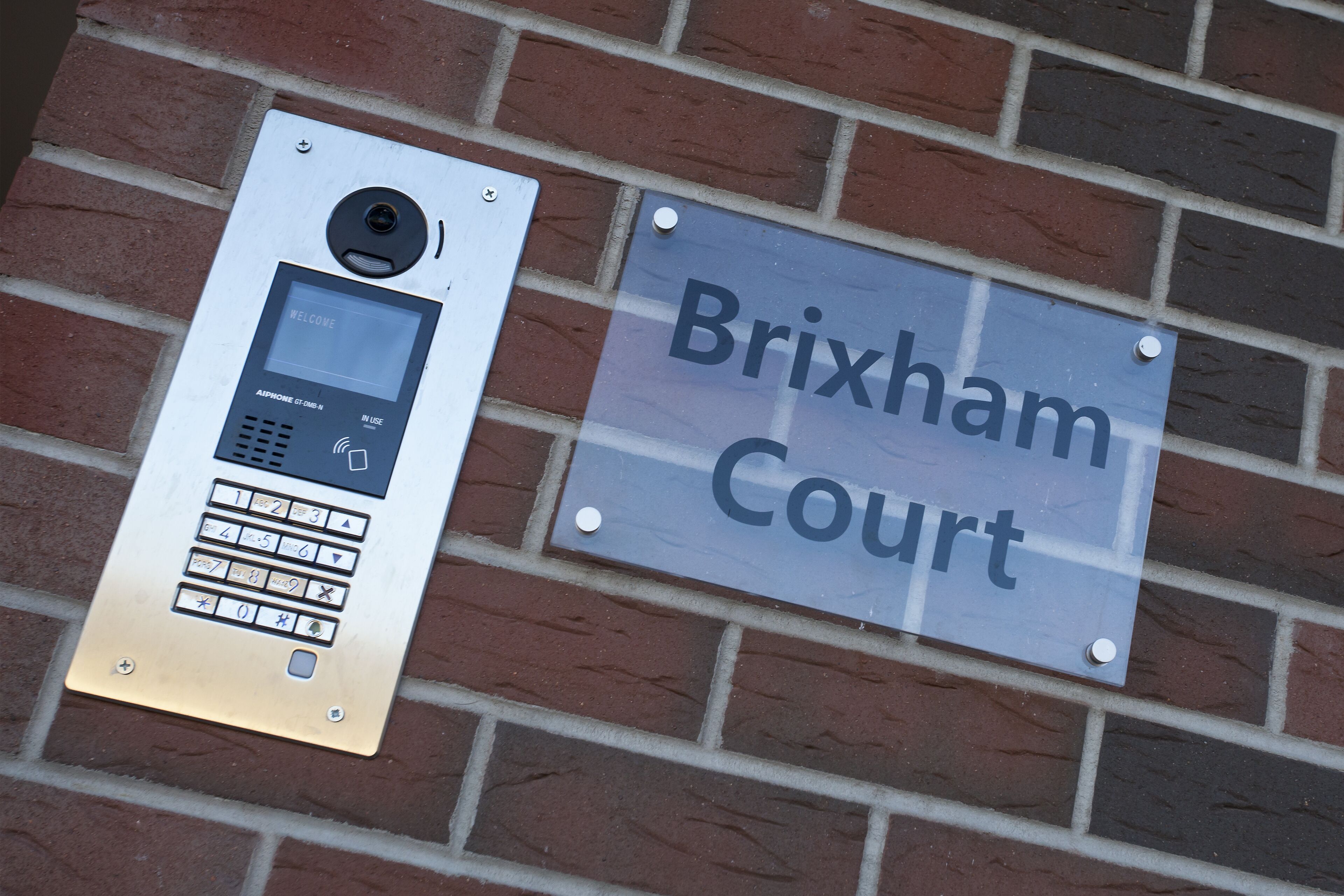 A digital keypad and a sign reading "Brixham Court".
