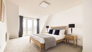 A bedroom with a bed, bedside tables, and a view of the outside. - Staines City Centre by Charles Hope (Staines)