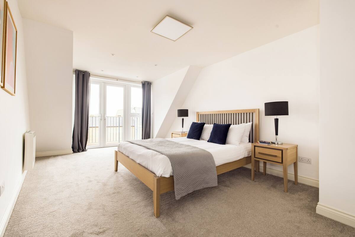 Ein Schlafzimmer mit Bett, Nachttischen und Blick ins Freie.