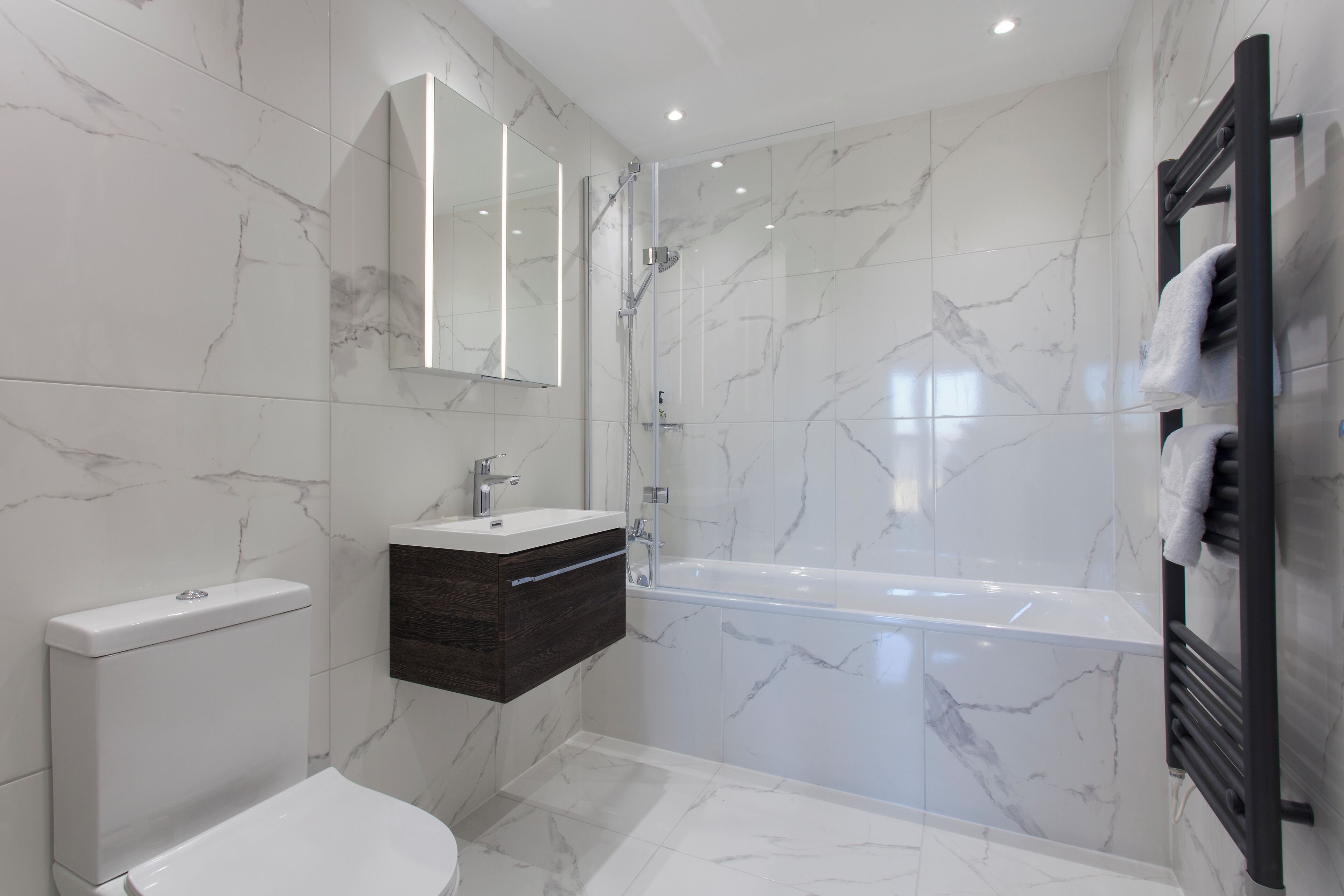 Een moderne badkamer met toilet, wastafel en bad.