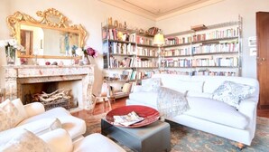 A living room with a fireplace, a white sofa, a bookshelf, and a mirror.