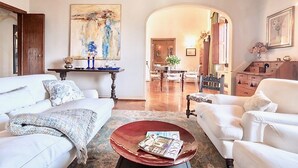 A living room with a white sofa, a coffee table with a magazine, and a painting on the wall.