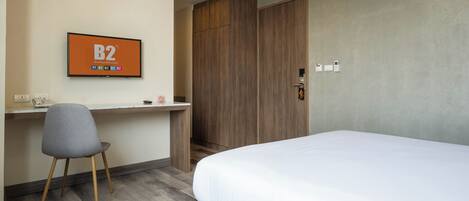 A hotel room with a bed, a desk, a chair, a wardrobe, and a sign on the wall.