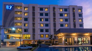 A multi-story hotel with a pool area, a fitness center, and a car parked in front. - B2 Korat Premier Hotel (Nakhon Ratchasima)