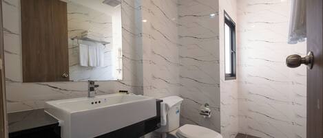 A modern bathroom with a white sink, toilet, and marble walls.