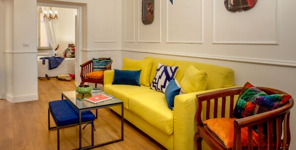 A living room with a yellow sofa, a glass coffee table, and a wooden chair. - Daplace - Flaminia Apartment (Rome)