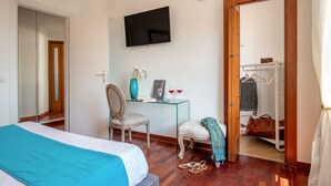 A hotel room with a bed, a desk with a chair, a television, and a wardrobe. - Daplace - Terenzia Apartment (Rome)
