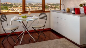 A small kitchen with a dining area, a view of the city, and a red vase with flowers. - Daplace - Terenzia Apartment (Rome)