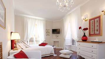 Quarto de hotel com duas camas, televisão, lareira e um candelabro.