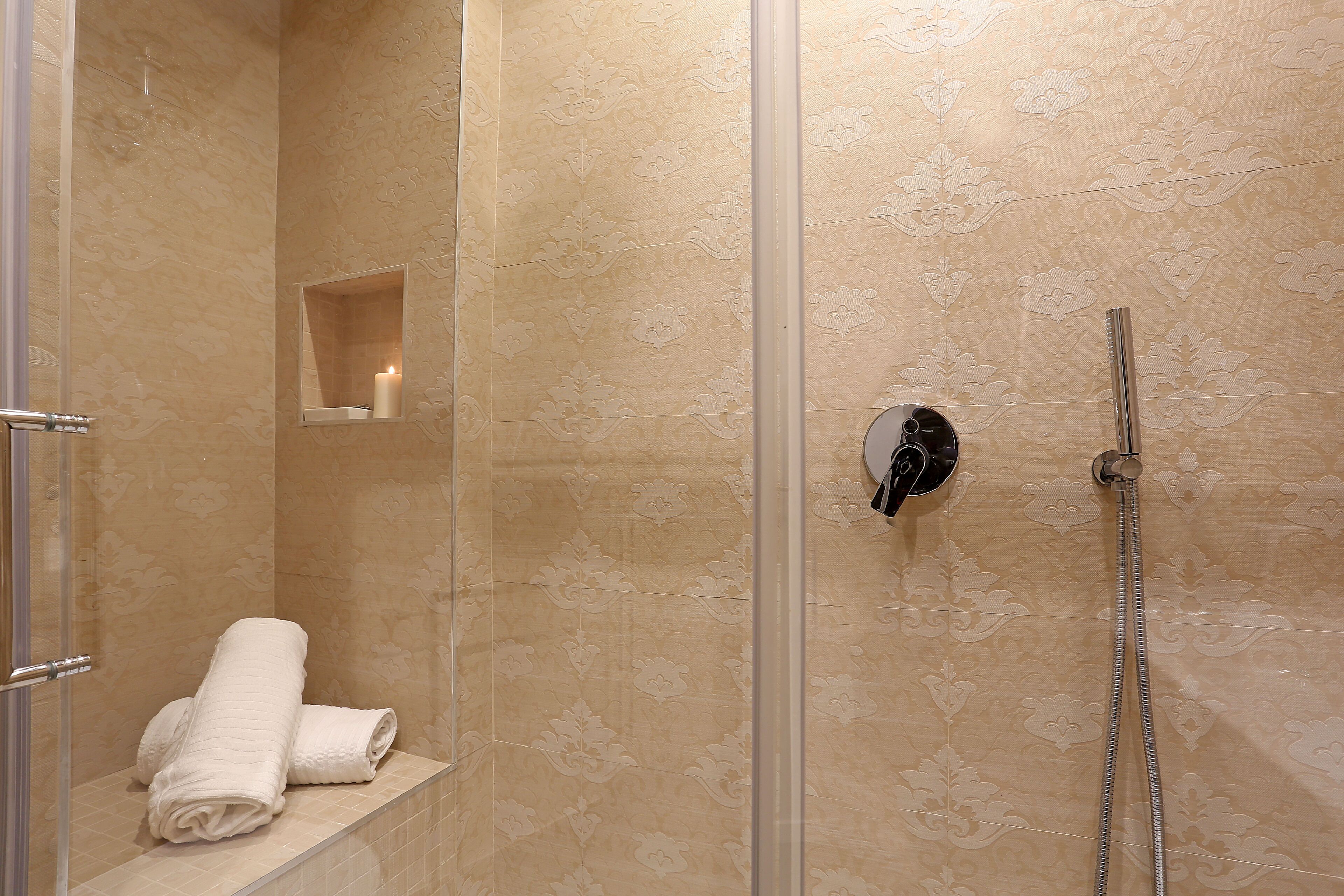 A shower with a glass door, a towel rack with towels, and a mirror.