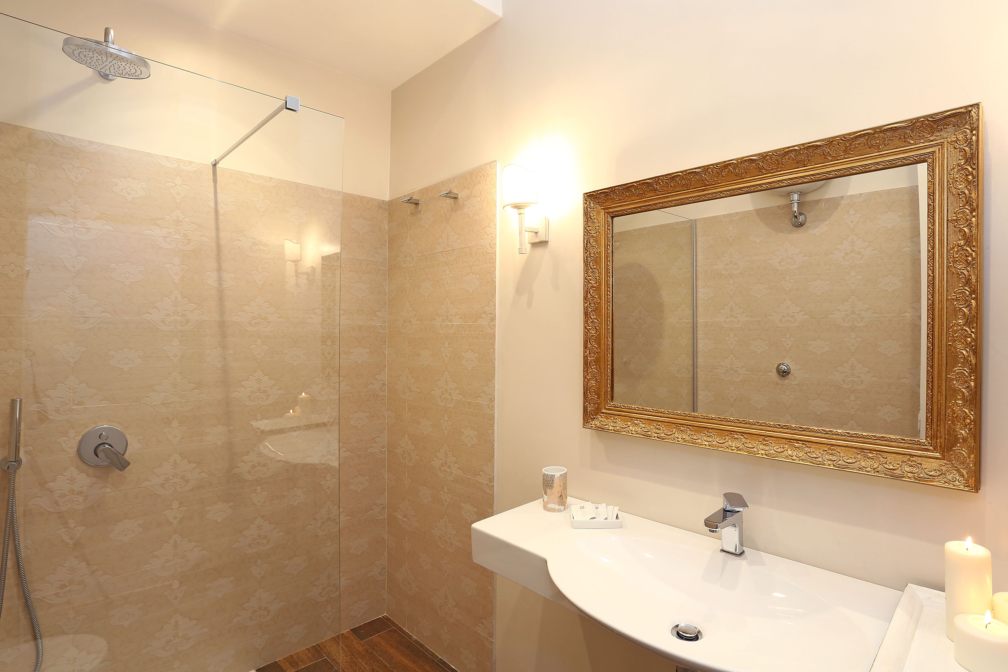 Un bagno con doccia, lavandino, specchio e un portalampada a parete.