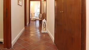 A hallway with a wooden door, a white wall, and a tiled floor. - Daplace - Gaia Apartment (Rome)