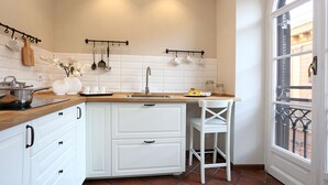 A kitchen with white cabinets, a wooden countertop, and a window with a view of the street. - Daplace - Gaia Apartment (Rome)