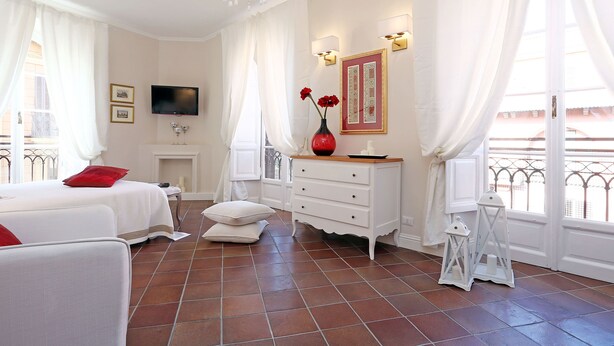 A hotel room with a bed, a dresser, a vanity, a TV, and a balcony view. - Daplace - Gaia Apartment (Rome)