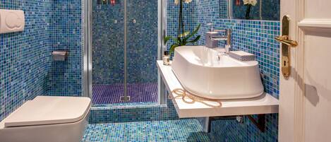 Une salle de bain avec un lavabo blanc, des toilettes et un espace douche agrémenté de carreaux de mosaïque bleus.