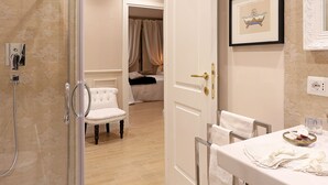 A bathroom with a shower, a chair, a vanity with a sink, and a mirror. - Daplace - Lucrezia Apartment (Rome)