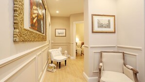 A hallway with two chairs, a framed painting, and a framed picture on the wall. - Daplace - Lucrezia Apartment (Rome)