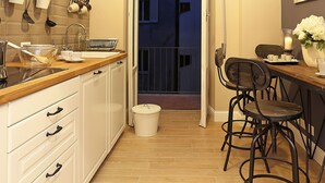 A narrow kitchen with white cabinets, a wooden countertop, and a dining area with bar stools. - Daplace - Lucrezia Apartment (Rome)