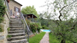 A stone staircase leading to a house with a pool, surrounded by greenery. - Arcobaleno (Loro Ciuffenna)