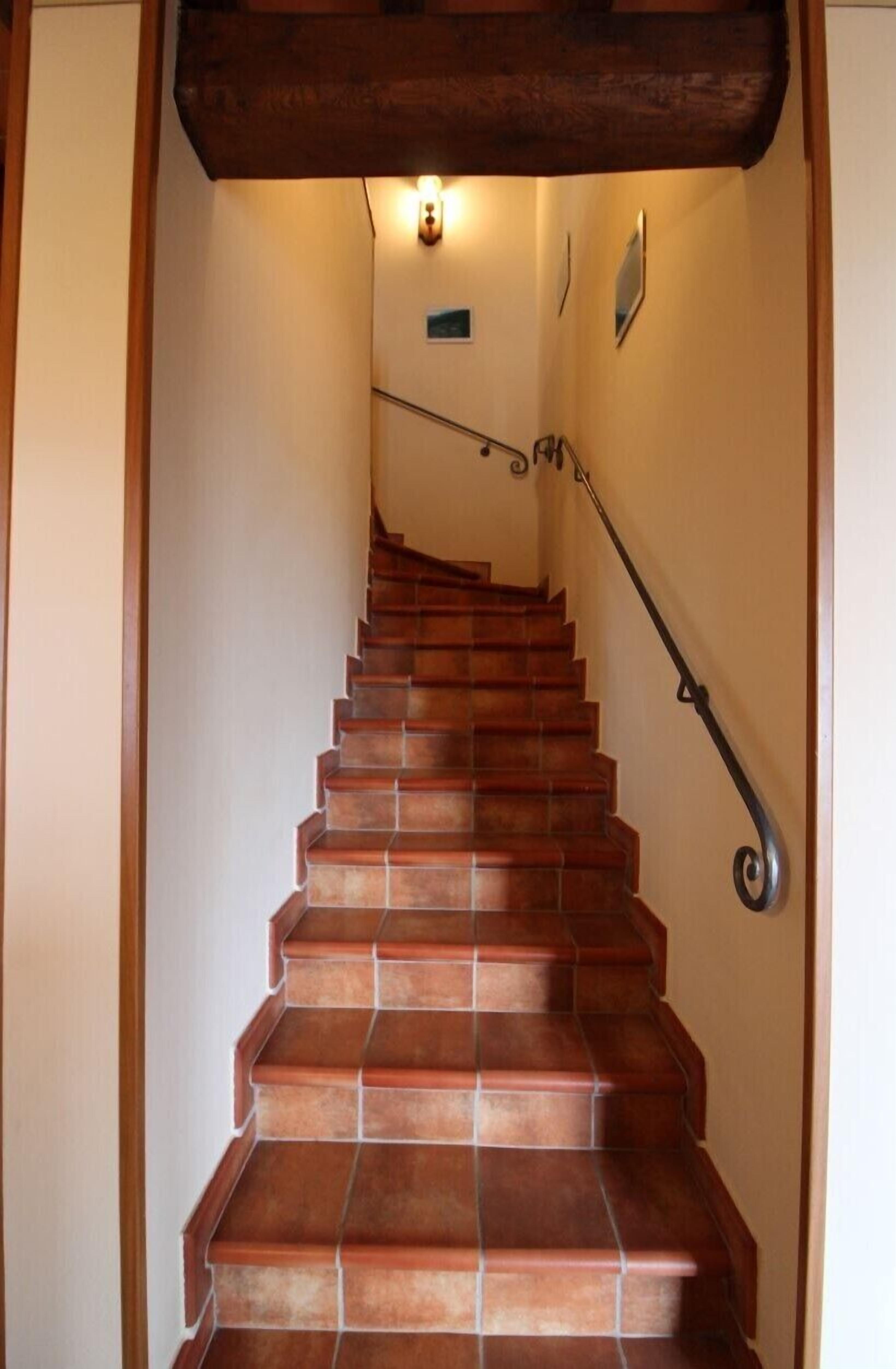 Una escalera de madera con barandilla y un accesorio de iluminación en la parte superior.