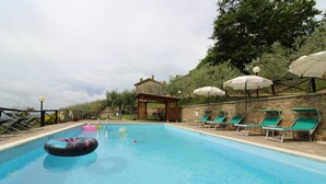 A swimming pool with inflatable toys, sun umbrellas, and lounge chairs.