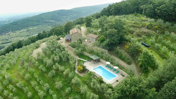 A secluded villa with a swimming pool surrounded by lush greenery and terraced fields.