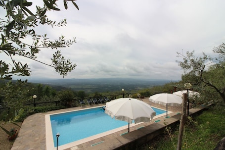 Una piscina al aire libre de temporada, sombrillas