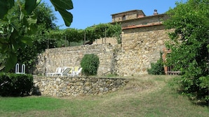 A stone wall with a small garden area, including a stone bench and a white chair.