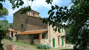 A stone building with a sloped roof, green shutters, and a brick chimney.