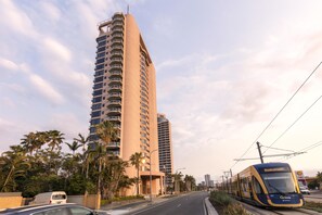 A modern high-rise building with multiple balconies, a tram line, and palm trees. - Oaks Gold Coast Hotel (Surfers Paradise)